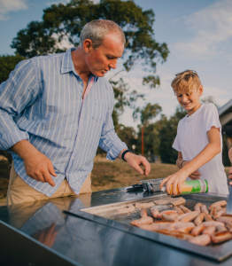 Dad and son cooking BBQ in backyard